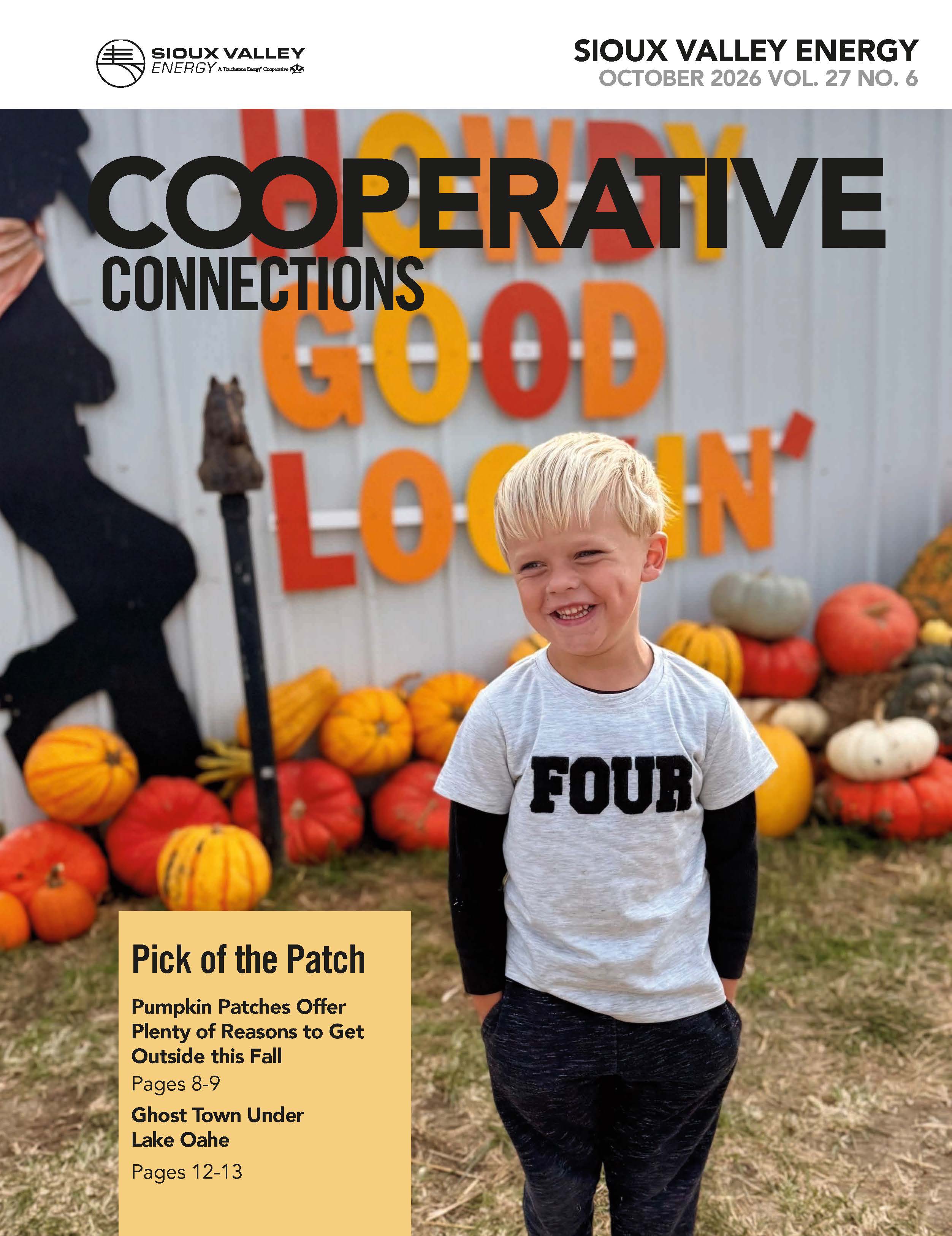 October Magazine cover showing a little boy standing infront of a metal building with the words "Howdy Good Lookin'" on it with orange, yellow and white pumpkins sitting in grass at base of building